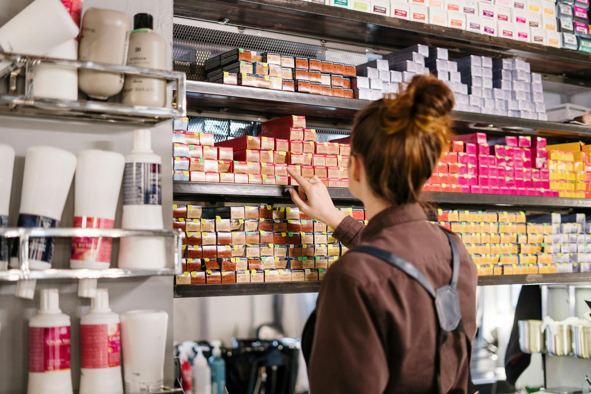 woman in gray jacket standing in front of white wooden shelf